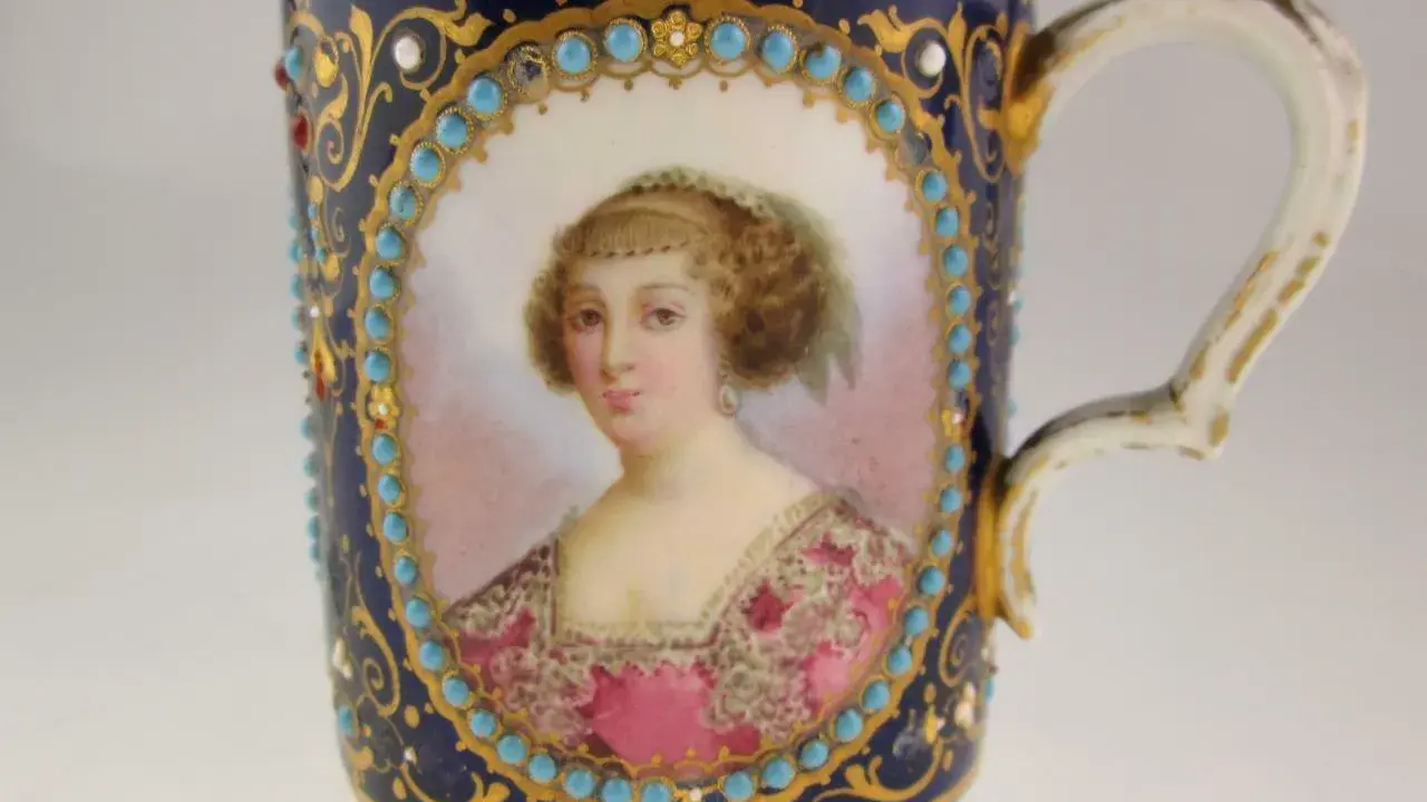 Tasse en porcelaine de Sèvres, ornée d'un portrait féminin, de turquoises et de dorures. La signature de la manufacture est discrètement intégrée.