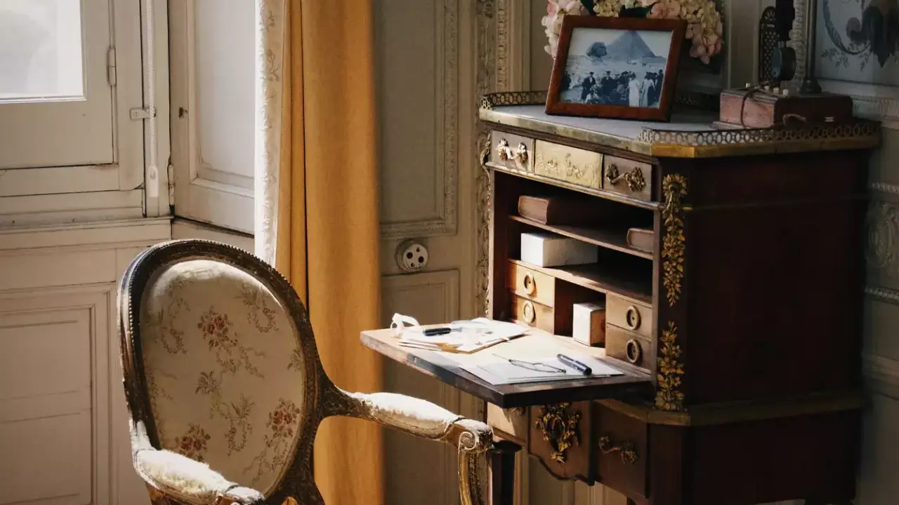 Bureau secrétaire ancien, fauteuil fleuri. Un tableau et des fleurs ornent le dessus. Idéal pour un coût inventaire mobilier succession.