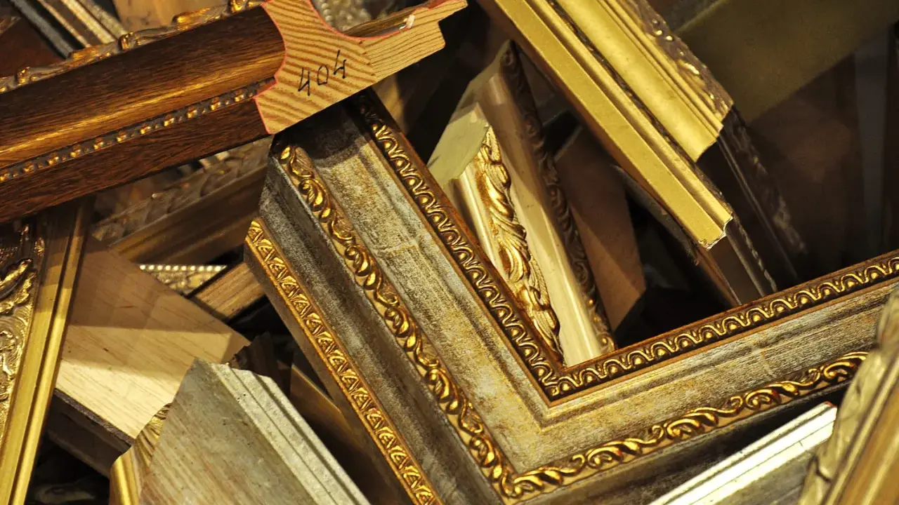 Empilement de cadres anciens dorés et patinés, prêts pour un nettoyage méticuleux.