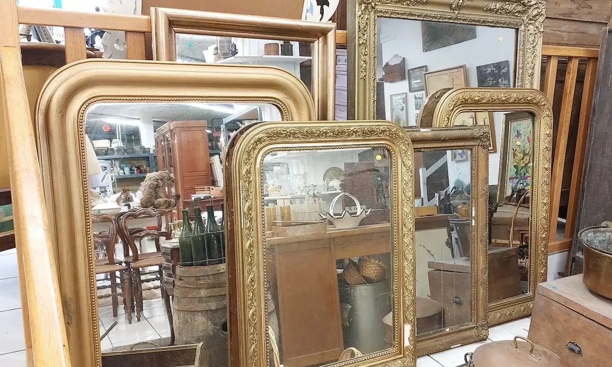 Plusieurs miroirs dorés, certains avec des cadres ornés, sont alignés. Comment reconnaître un miroir Napoléon III ? Cherchez les moulures riches et les détails sculptés.