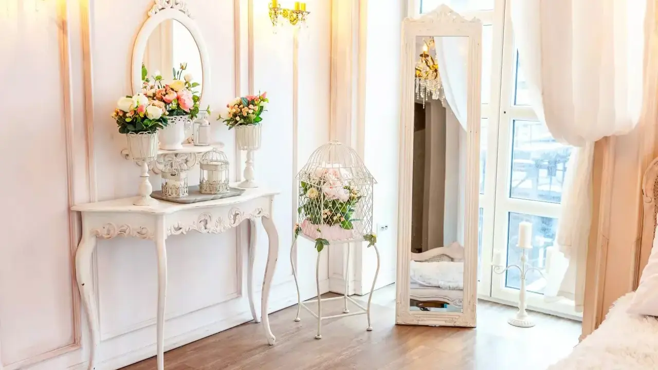 Un boudoir romantique dans un style baroque, avec une console ornée de fleurs, une cage à oiseaux décorative et un grand miroir.