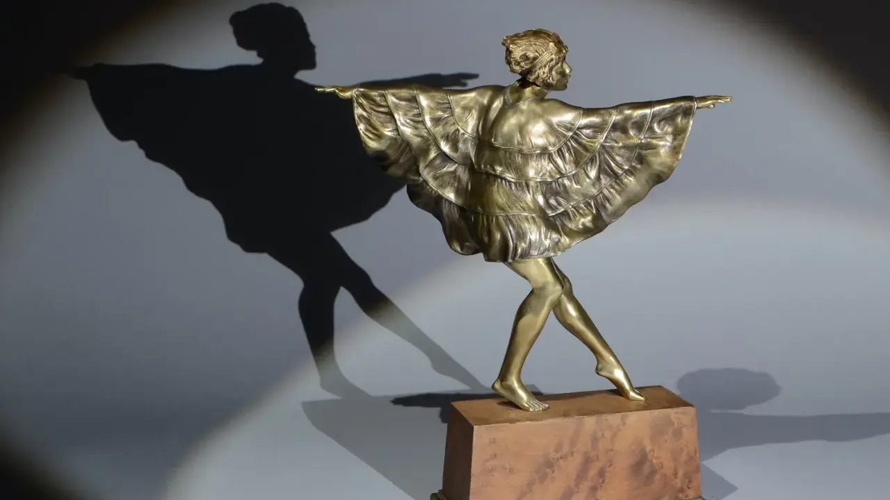 Sculpture en bronze d'une danseuse par Marcel Bouraine, sa robe à volants flottant, projetant une ombre gracieuse.