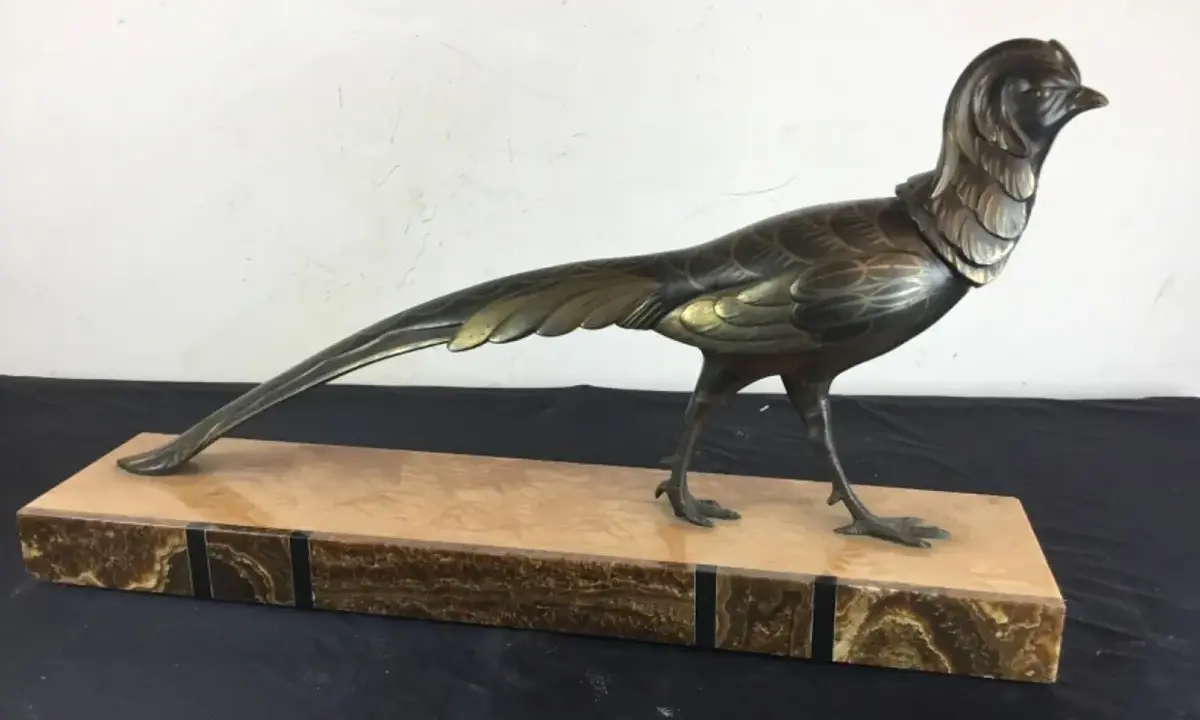 Sculpture d'oiseau en bronze, style Irénée Rochard, sur un socle en marbre veiné. L'oiseau, aux détails fins, arbore une longue queue élégante.