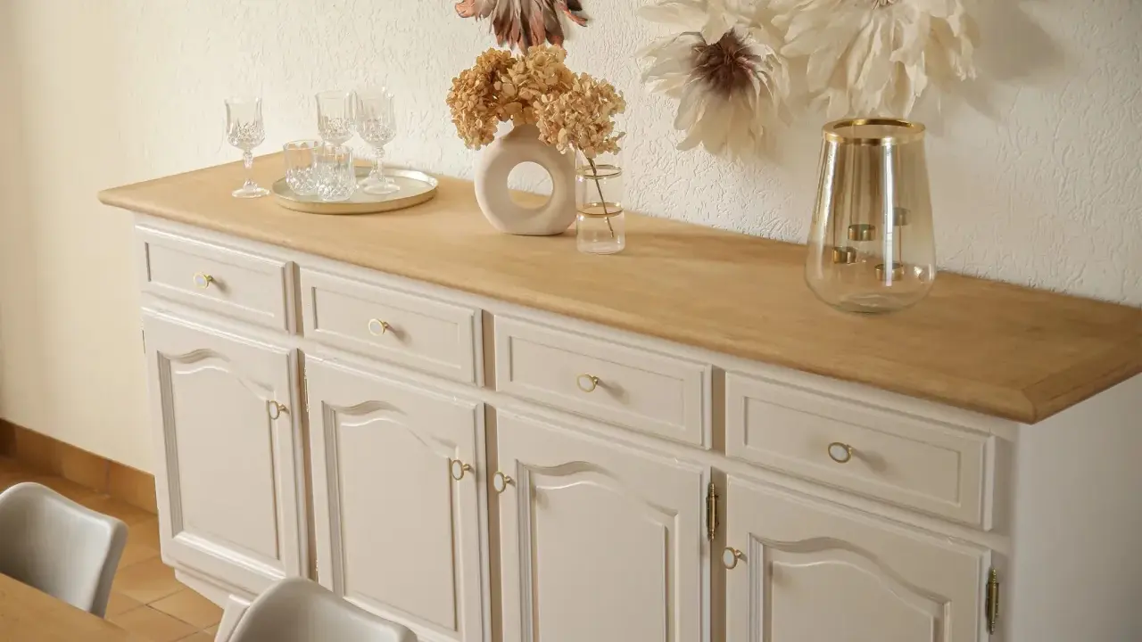 Buffet année 30 repeint, avec un plateau en bois clair. Des verres et un vase décorent le dessus.