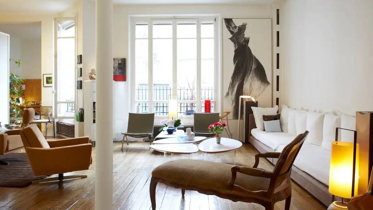Un salon lumineux où les meubles anciens reviennent à la mode, avec un fauteuil vintage, une méridienne et une grande œuvre d'art.
