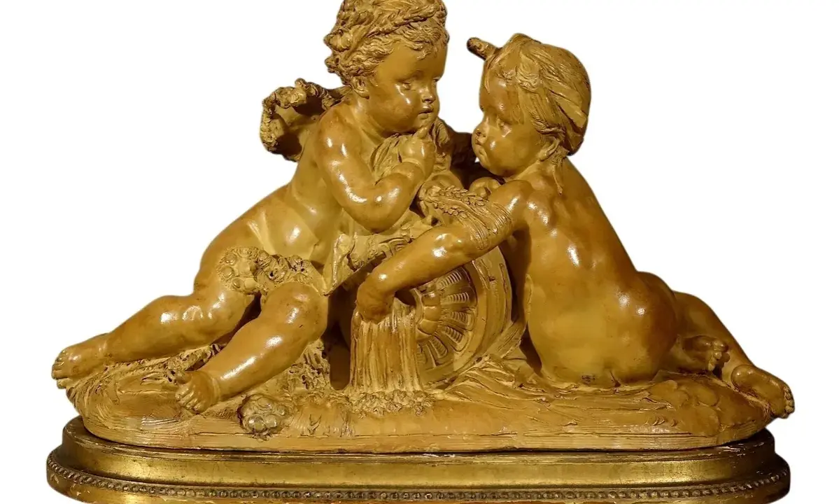 Sculpture en terre cuite d'une carrier-belleuse, deux angelots jouant avec une roue ornée de guirlandes.