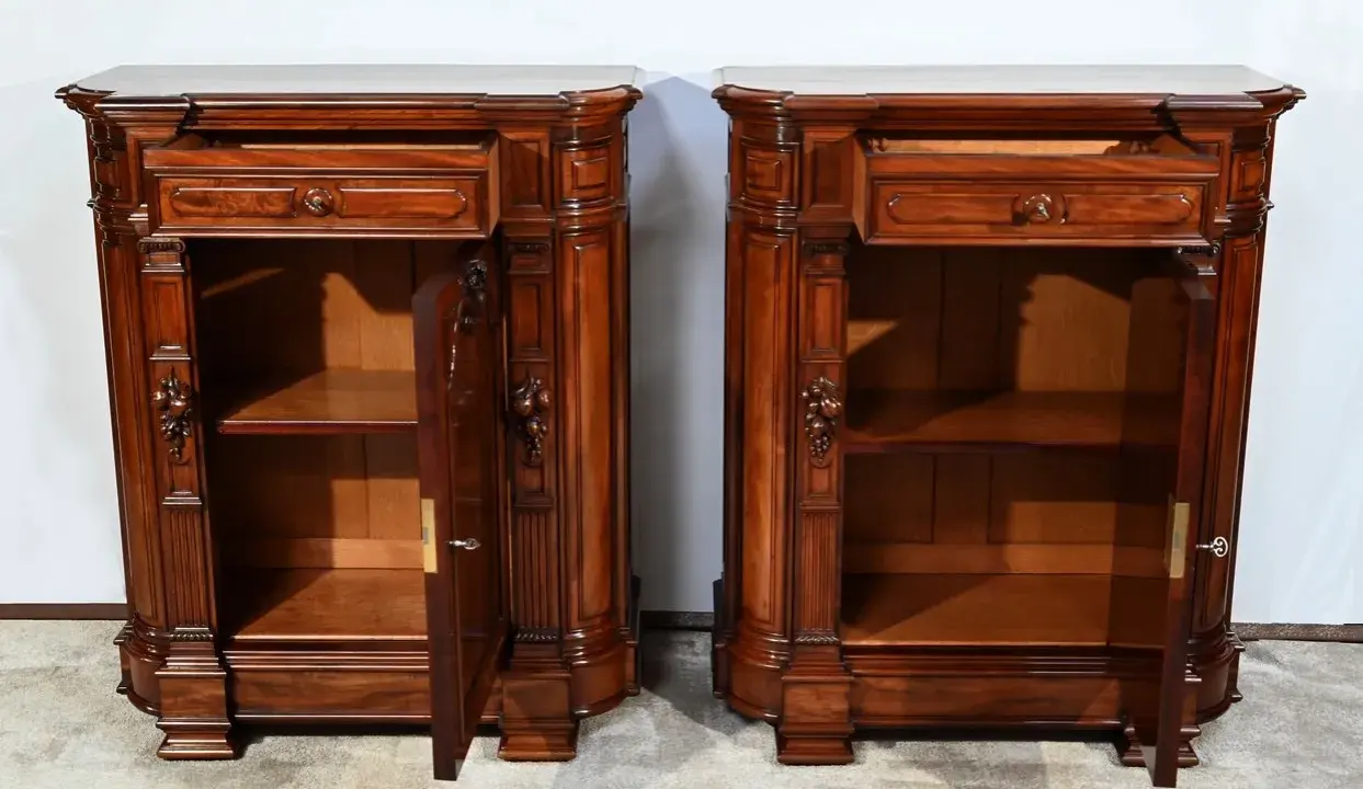 Paire de commodes en bois sombre, style mobilier Napoléon III, avec tiroirs et portes sculptées.