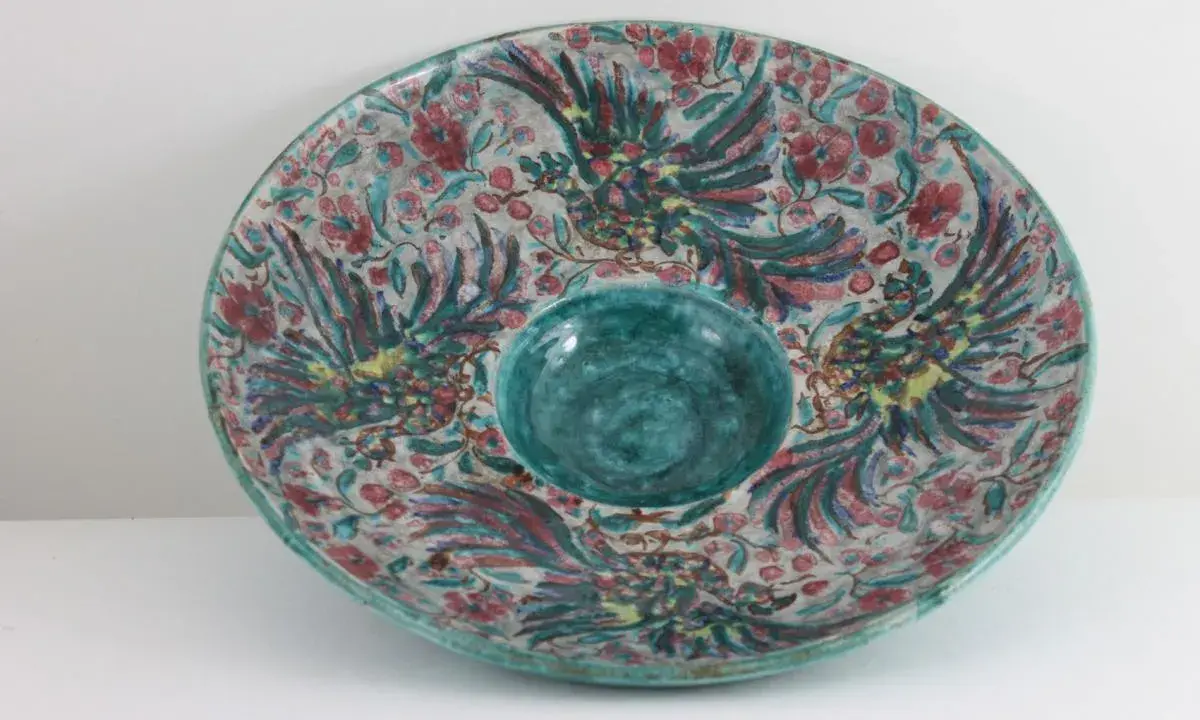 Plat décoratif en céramique, style Édouard Cazaux, orné d'oiseaux stylisés et de fleurs, avec un centre creux bleu turquoise.
