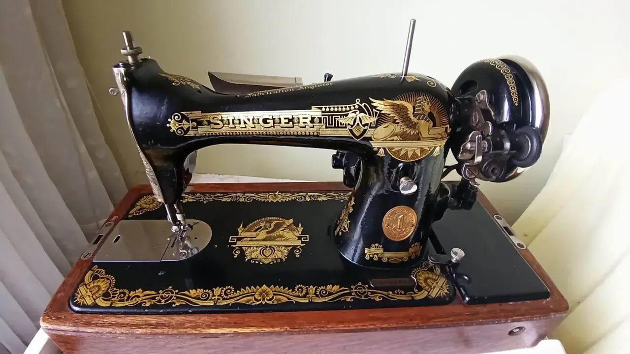Machine à coudre Singer ancienne, noire et dorée, sur son socle en bois. Le numéro de série est visible pour une estimation.