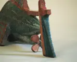 Sculpture de poisson en céramique, style Jean Derval, aux couleurs vives bleu-vert et rouge, avec une hélice visible.