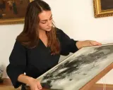 Une femme examine un tableau abstrait, cherchant des indices pour comment estimer un tableau avec signature.