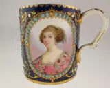 Tasse en porcelaine de Sèvres, ornée d'un portrait féminin, de turquoises et de dorures. La signature de la manufacture est discrètement intégrée.