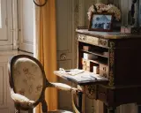 Bureau secrétaire ancien, fauteuil fleuri. Un tableau et des fleurs ornent le dessus. Idéal pour un coût inventaire mobilier succession.