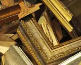 Empilement de cadres anciens dorés et patinés, prêts pour un nettoyage méticuleux.