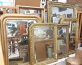 Plusieurs miroirs dorés, certains avec des cadres ornés, sont alignés. Comment reconnaître un miroir Napoléon III ? Cherchez les moulures riches et les détails sculptés.