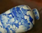 Vase en porcelaine bleue et blanche orné d'une scène complexe, portant un sceau porcelaine signature chinoise.