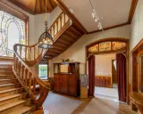 Escalier majestueux en bois, vitraux colorés, mobilier ancien. Un intérieur d'une élégance intemporelle, évoquant le style Majorelle.
