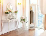 Un boudoir romantique dans un style baroque, avec une console ornée de fleurs, une cage à oiseaux décorative et un grand miroir.