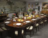 Table dressée dans un style directoire, avec fruits, fleurs et vaisselle raffinée. Le décor mural évoque un paysage champêtre.