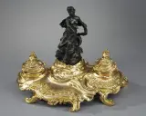 Encre dorée rocaille, ornée d'une femme drapée et d'un dauphin, évoquant l'élégance de l'époque Louis XV.