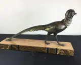 Sculpture d'oiseau en bronze, style Irénée Rochard, sur un socle en marbre veiné. L'oiseau, aux détails fins, arbore une longue queue élégante.