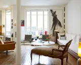 Un salon lumineux où les meubles anciens reviennent à la mode, avec un fauteuil vintage, une méridienne et une grande œuvre d'art.