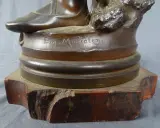 Signature "Eug. Marioton" gravée sur la base d'une sculpture en bronze patiné, posée sur un socle en marbre rouge.