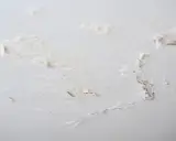 Détails d'un plafond abîmé, avec des morceaux de peinture écaillée révélant le plâtre sous-jacent, signe de salpêtre sur le mur.