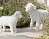Deux adorables agneaux en résine, œuvres de sculpteurs animaliers, semblent converser au milieu d'une végétation luxuriante.