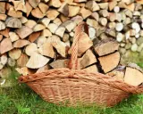 Panier en osier rempli de bois de chauffage, prêt à être utilisé pour protéger le bois de l'humidité.