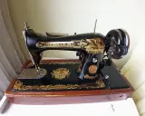 Machine à coudre Singer ancienne, noire et dorée, sur son socle en bois. Le numéro de série est visible pour une estimation.