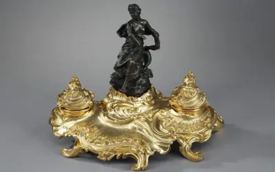 Encre dorée rocaille, ornée d'une femme drapée et d'un dauphin, évoquant l'élégance de l'époque Louis XV.