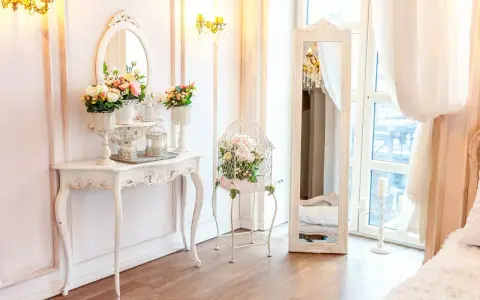 Un boudoir romantique dans un style baroque, avec une console ornée de fleurs, une cage à oiseaux décorative et un grand miroir.