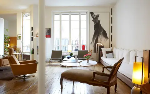 Un salon lumineux où les meubles anciens reviennent à la mode, avec un fauteuil vintage, une méridienne et une grande œuvre d'art.