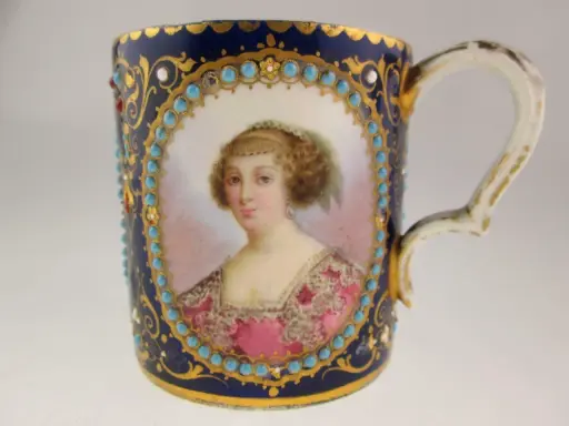Tasse en porcelaine de Sèvres, ornée d'un portrait féminin, de turquoises et de dorures. La signature de la manufacture est discrètement intégrée.