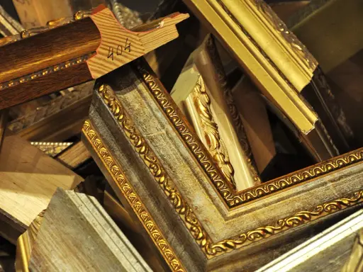 Empilement de cadres anciens dorés et patinés, prêts pour un nettoyage méticuleux.
