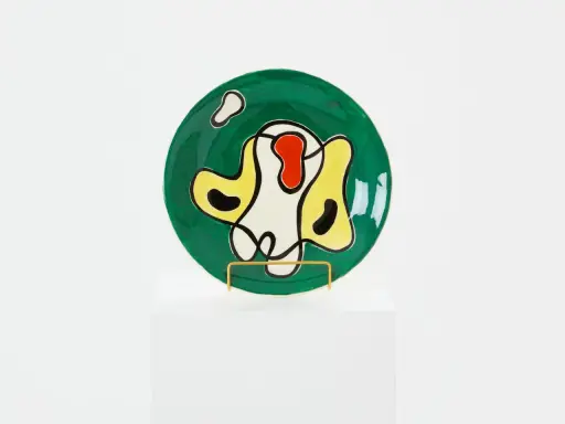 Assiette ronde verte ornée de formes abstraites noires, jaunes, rouges et blanches, dans le style de Roland Brice.