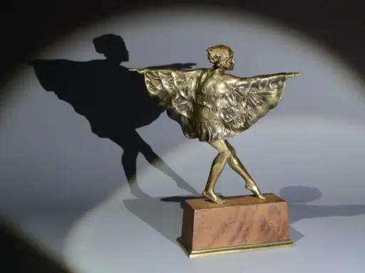 Sculpture en bronze d'une danseuse par Marcel Bouraine, sa robe à volants flottant, projetant une ombre gracieuse.
