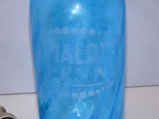 Bouteille ancienne en verre bleu pour eau de seltz, gravée "EAUX DE PENNES". Un objet de collection qui évoque le prix d'une eau gazeuse d'antan.