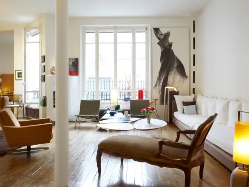 Un salon lumineux où les meubles anciens reviennent à la mode, avec un fauteuil vintage, une méridienne et une grande œuvre d'art.