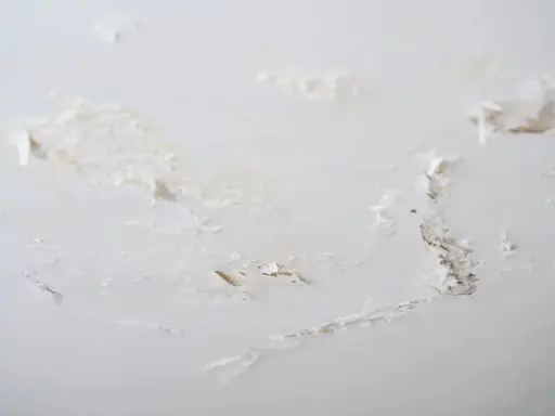 Détails d'un plafond abîmé, avec des morceaux de peinture écaillée révélant le plâtre sous-jacent, signe de salpêtre sur le mur.