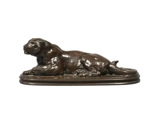 Sculpture en bronze d'un lion couché, œuvre du sculpteur Barye. La signature est discrète.