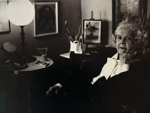 Colette Gueden, artiste peintre, dans son atelier, entourée de ses œuvres et de son matériel.