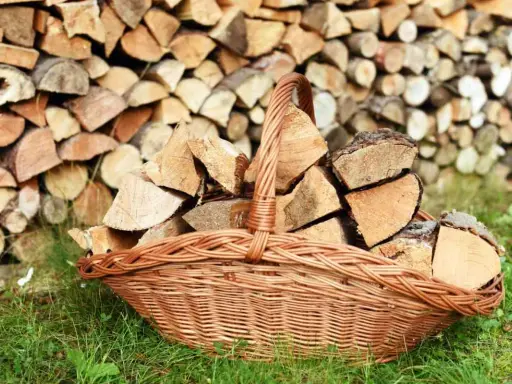 Panier en osier rempli de bois de chauffage, prêt à être utilisé pour protéger le bois de l'humidité.