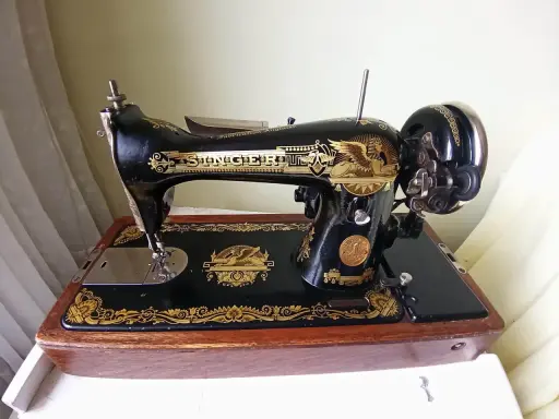 Machine à coudre Singer ancienne, noire et dorée, sur son socle en bois. Le numéro de série est visible pour une estimation.