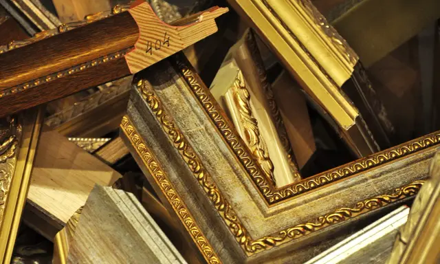 Empilement de cadres anciens dorés et patinés, prêts pour un nettoyage méticuleux.