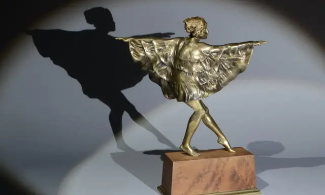 Sculpture en bronze d'une danseuse par Marcel Bouraine, sa robe à volants flottant, projetant une ombre gracieuse.