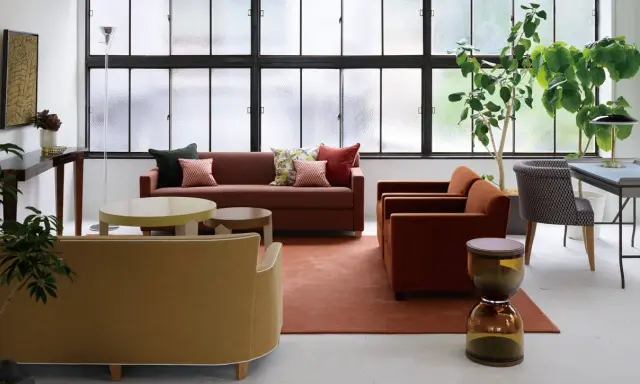 Salon moderne avec canapés confortables, tables basses et plantes vertes. Le mobilier Hurel apporte une touche d'élégance.