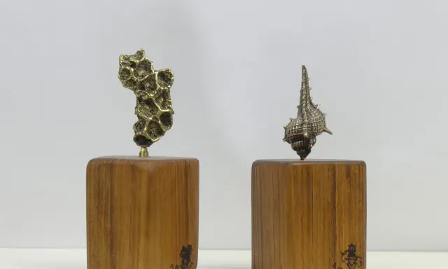 Deux sculptures en bronze, l'une abstraite, l'autre en forme de coquillage, sur des socles en bois portant la signature des fondeurs de bronze.