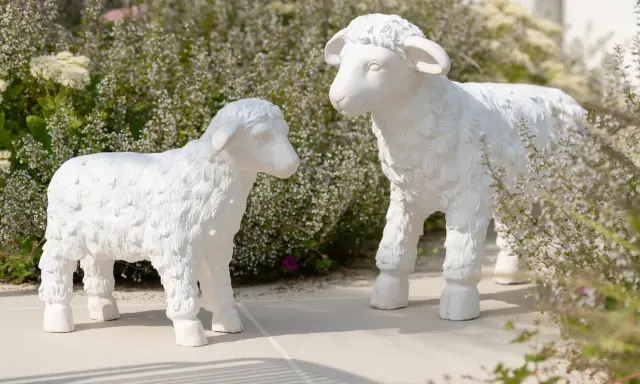 Deux adorables agneaux en résine, œuvres de sculpteurs animaliers, semblent converser au milieu d'une végétation luxuriante.